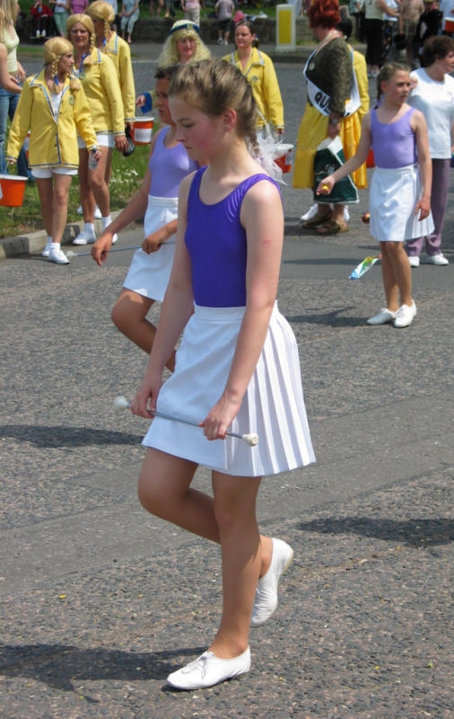 Blonde Majorette with Bare Legs wearing White Pleated Miniskirt and White Sneakers